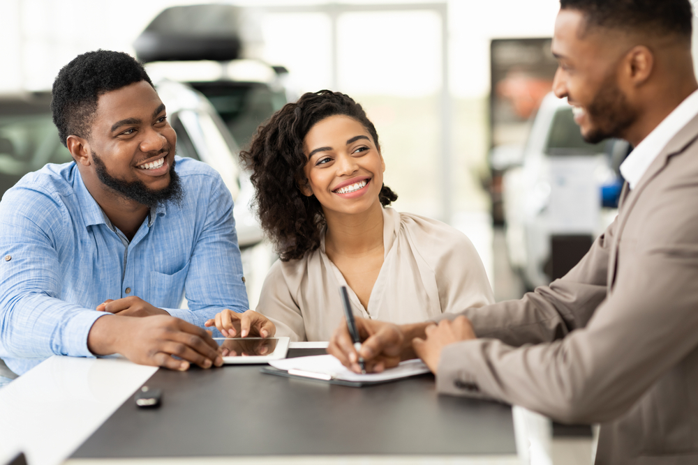 Happy,Afro,Couple,Buying,New,Car,Signing,Papers,With,Salesman